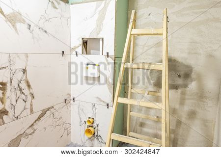 Bathroom Renovation Concept. Marble Ceramic Tiles With Spacers And Grey Cement Walls In Bathroom, Re