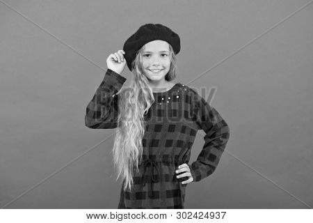 Kid Little Cute Girl With Long Blonde Hair Posing In Beret Hat And Checkered Dress Red Background. F