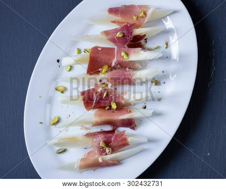 Still life of jamon serrano with yellow melon