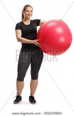 Full length portrait of a young smiling woman posing with a fitness ball isolated on white background