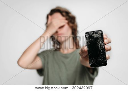 Upset Young Woman Holding Her Broken Smartphone. Phone Screen Need To Repair. Isolated On Gray Backg