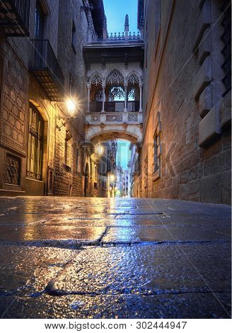Illuminated Medieval Street Carrer Del Bisbe With Bridge Of Sighs In Barri Gothic Quarter, Barcelona