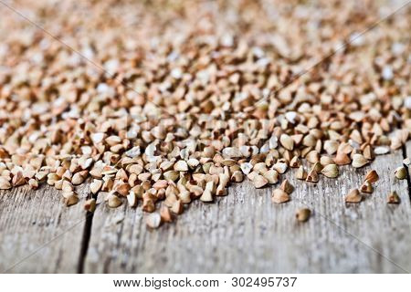 Organic green dry buckwheat seads closeup on rustic wooden background. Buckwheat texture.