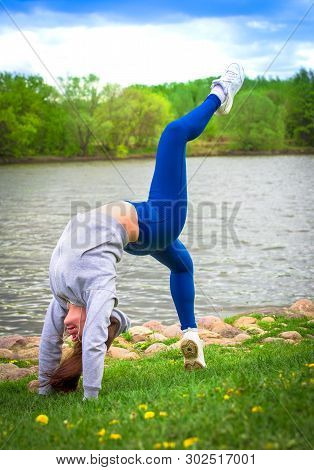 Young Girl Goes In For Sports In Nature. Healthy Lifestyle.flaxible Child Doing Joga Poses Bridge St