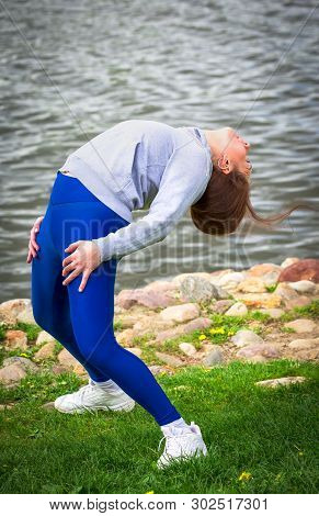 Young Girl Goes In For Sports In Nature. Healthy Lifestyle.flaxible Child Doing Joga Poses Bridge St