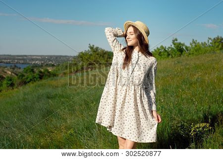Half Length Portrait Of A Charming Positive Woman Dressed In Long White Summer Dresses With A Straw 