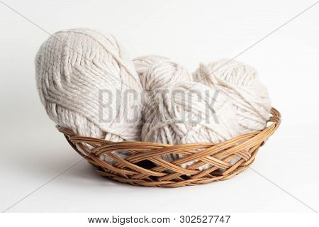 Wool Yarn In Coils And Baals Of Wool With Knitting Needles In Basket