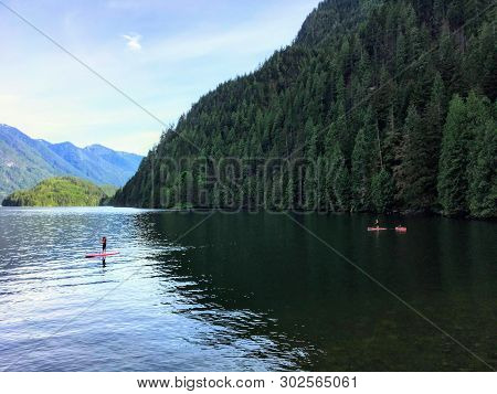 Teenagers Paddle Boarding And Kayaking On A Beautiful Evening, In A Remote Inlet In British Columbia