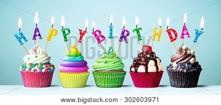 Colorful cupcakes with candles spelling Happy Birthday
