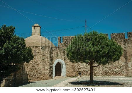 Elvas, Portugal - July 07, 2018. Stone Wall With Door And Small Tree On A Sunny Day, In Front Of The