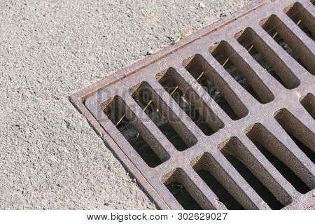 Metal Grille Closing The Opening Of The Storm Water Flow, Urban Photography In The Summer On A Sunny