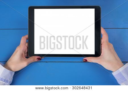 Woman Sitting And Looking At Digital Tablet Computer Device With White Blank Screen On Blue Wooden T
