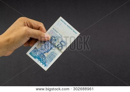 Hand Holding Fifty Croatian Kuna Or Sto Kuna Bank Notes On Black Background. Financial Concept And S