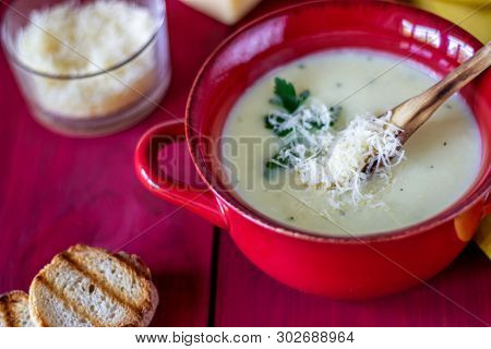 Cheese Cream Soup On A Red Wooden Background. White Bread Croutons. Ingredients.