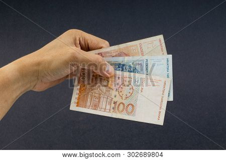 Hand Holding Fifty Croatian Kuna Or Sto Kuna Bank Notes On Black Background. Financial Concept And S