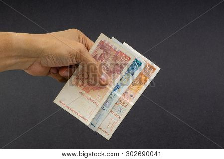 Hand Holding Fifty Croatian Kuna Or Sto Kuna Bank Notes On Black Background. Financial Concept And S