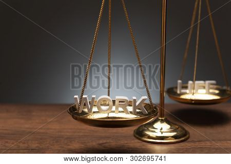 Gold Brass Balance Scale On Wooden Desk And Gray Backdrop With 3d Text 