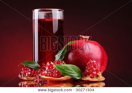 rijpe pomergranate en glas sap op rode achtergrond