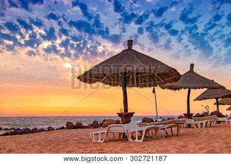Deck Chairs With Umrellas On The Beach With Beautiful Sunset In Senegal, Africa. There Is Blue Sky A