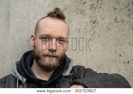 Serious Or Calm Young Bearded Man Sitting In Front Of The Camera