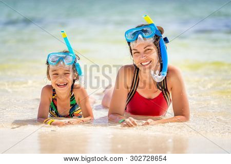 Young mother and little daughter in snorkeling masks enjoing the beach in Dominican Republic