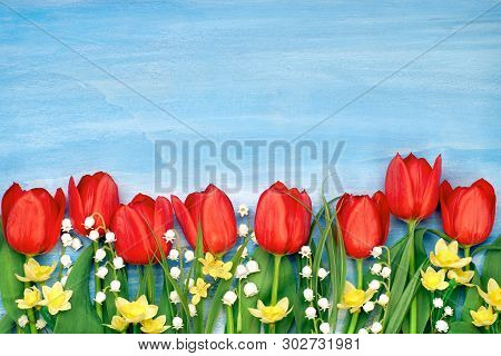 Border Of Red Tulips, Daffodils And Lily Of The Valley Flowers On Rustic Background. Space For Your 