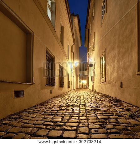 Old Narrow Street In Prague, Mala Strana, Late In The Evening With Street Lights Reflected In Cobble
