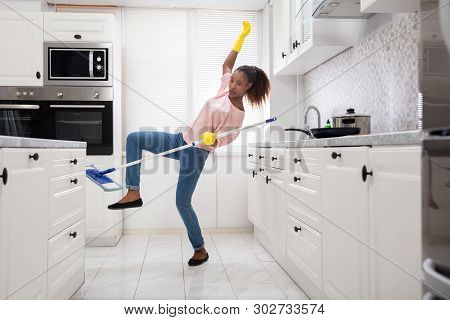 Close-up Of A Young African Woman Slipping While Mopping Floor In The Kitchen