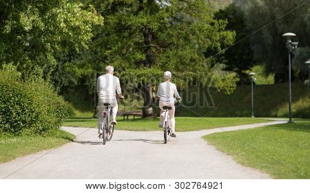 active old age, people and lifestyle concept - happy senior couple riding bicycles at toom park in summer city of tallinn, estonia