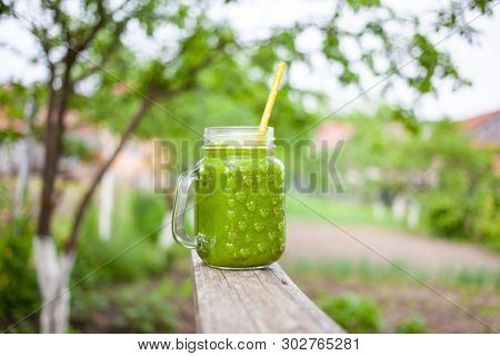  a jar with green cold-pressed juice, nature background. Healthy eating, detoxing, juicing, body cleancing concept 