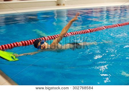 Swimming lessons for kids in sport school, little boy practising swimming in the pool