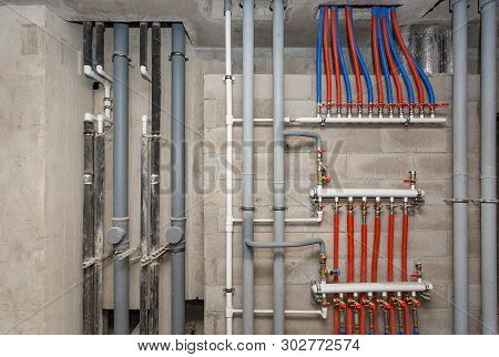 Pipes Of Heating And Water Supply System On The Background Of A Concrete Wall.