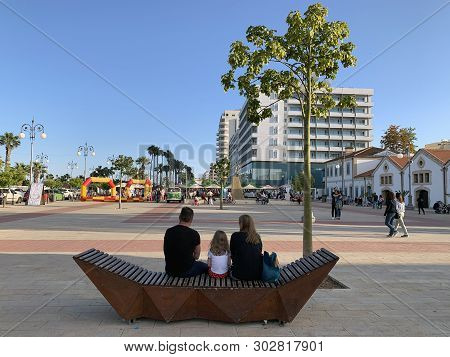 Larnaka, Cyprus - May 11, 2019: Family Sitting On A Bench On The Promenade Phinikoudes Near The Sea