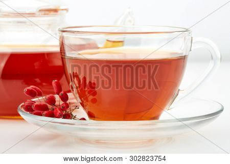 Healthy tea with barberries in glass cup on on a white background.