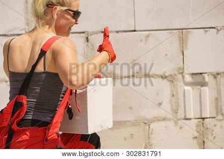 Strong Pretty Woman Working On Construction Site, Building House, Installing Gray Airbricks. Industr