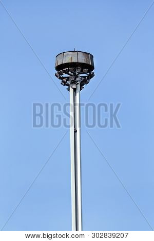 Tower With Reflectors At The Roundabout On The City Road And Street. Lighting Pole With Blue Sky. Bi