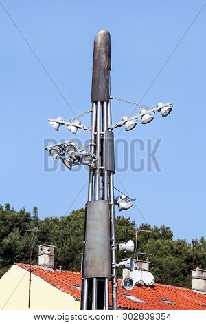Tower With Reflectors At The Roundabout On The City Road And Street. Lighting Pole With Blue Sky. Bi
