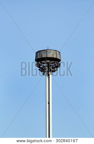 Tower With Reflectors At The Roundabout On The City Road And Street. Lighting Pole With Blue Sky. Bi