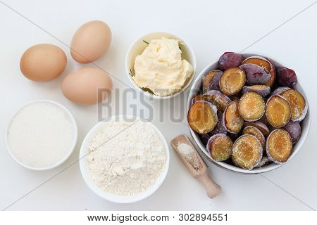 Ingredients For Plum Pie Baking On A White Background: Butter, Flour, Sugar, Baking Powder, Eggs, Fr