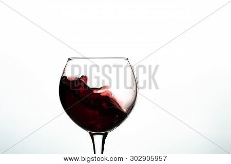 Red Wine Splash Into Glass On White Background.