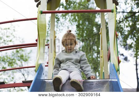 Surprised Child Looks At The Children Slide On The Playground