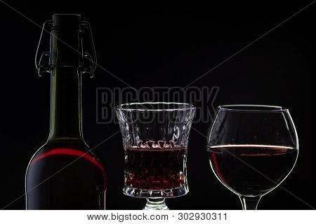 Wine. Red Wine In Two Wine Glasses Over Dark Background. Silhouette Of Bottle With Rose Wine And Ope