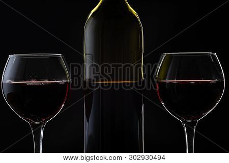 Wine. Red Wine In Two Wine Glasses Over Dark Background. Silhouette Of Bottle With Rose Wine