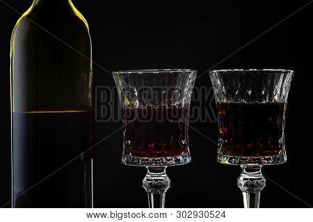 Wine. Red Wine In Two Wine Glasses Over Dark Background. Silhouette Of Bottle With Rose Wine