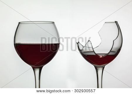 Broken And Not Broken Wine Glass With Red Wine On White Background.