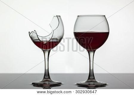 Broken And Not Broken Wine Glass With Red Wine On White Background.