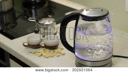 Tea Kettle With Boiling Water. Tea Bags And Sugar On The Background. Water Boiling In Kettle.