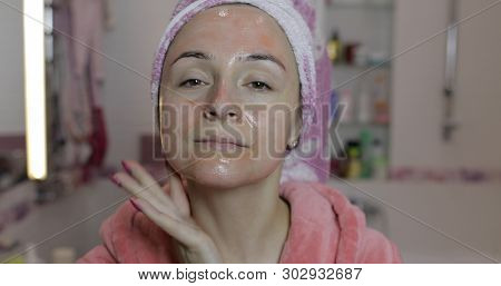 Woman Applying Mask Moisturizing Skin Cream On Face And Looking At Camera In Bathroom. Girl Taking C