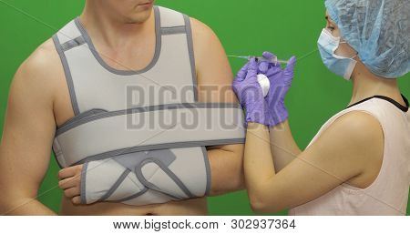 Man With Shoulder Injury. Nurse With Syringe With Medicines Makes Prick From Pain. Patient In A Band