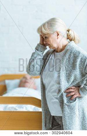 Upset Senior Woman And Man In Coma In Clinic
